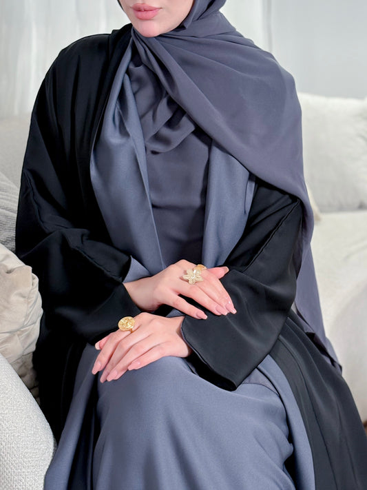 Person wearing a black and gray abaya sitting on a white couch.